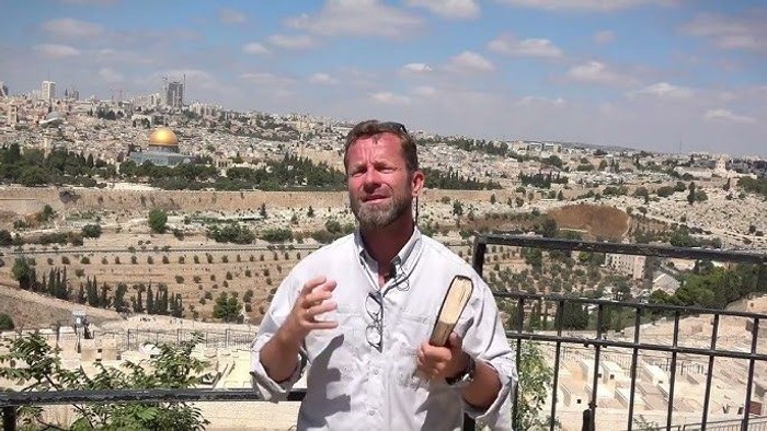 Mann posiert vor historischer Stadtlandschaft mit goldenem Dome im Hintergrund.