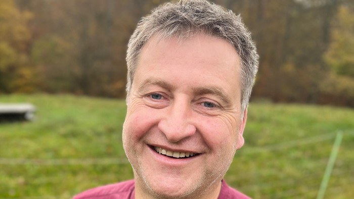 Mann mit grauen Haaren lacht in rotem Hemd im Freien
