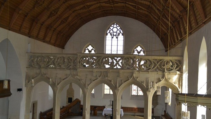 Große, hell erleuchtete Kirche mit hohen Bögen und Buntglasfenstern