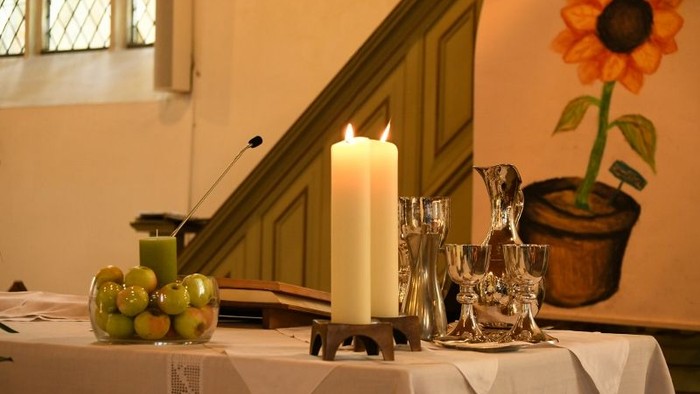 Ein Tisch mit Kerze, Obst und Gläsern in einem Raum mit Treppe und Sonnenblume