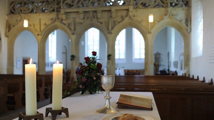 In der Kirche stehen zwei Kerzen, ein Kelch und ein Buch auf dem Tisch.