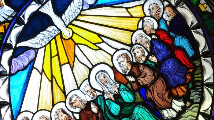 Das Buntglasfenster zeigt eine religiöse Szene mit mehreren Personen und einem Strahlenkranz.