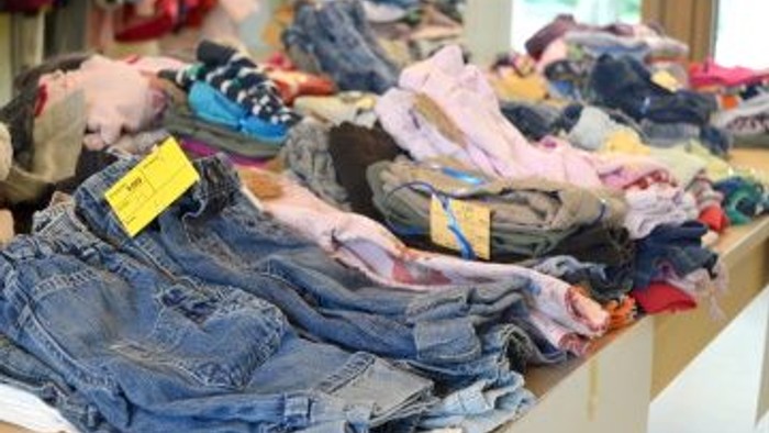 Auf dem Bild sind mehrere Kisten mit gefalteter Kleidung, darunter Jeans und T-Shirts, zu sehen.