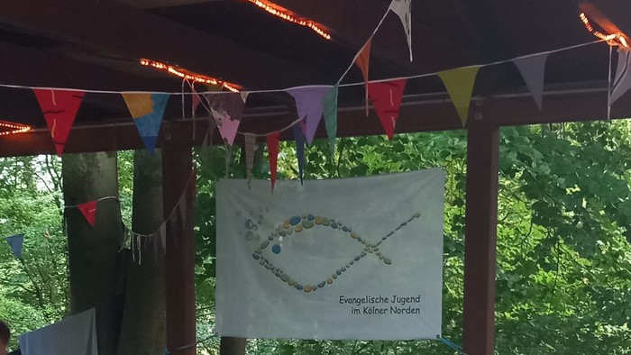 Gruppe von Menschen sitzt an Tischen unter einem Pavillon im Freien