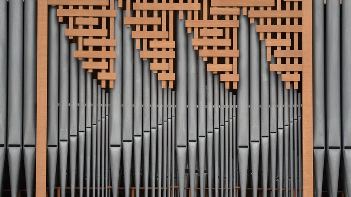 Das Bild zeigt eine Nahaufnahme von Orgelpfeifen mit Holzdekor.