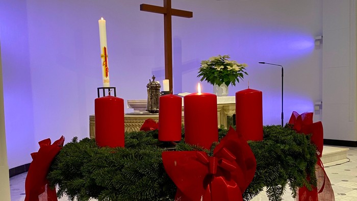 Kirchenaltar mit roten Kerzen und Grünpflanzen.