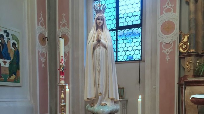 Heilige Statue in Kirche mit Blumen und Kerzen