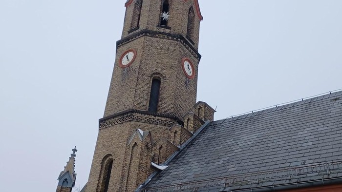 Kirche mit Uhrturm und steilem Dach.