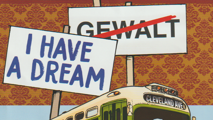 Das Bild zeigt einen Bus mit verschiedenen Schildern, darunter "Gleichheit & Gerechtigkeit", "GEWALT" mit einem roten Strich durchgezogen und "I HAVE A DREAM".
