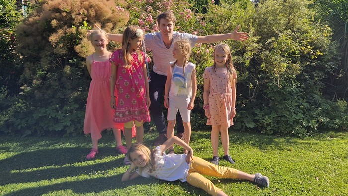 Familie genießt Zeit im Garten, ein Mädchen liegt auf dem Gras