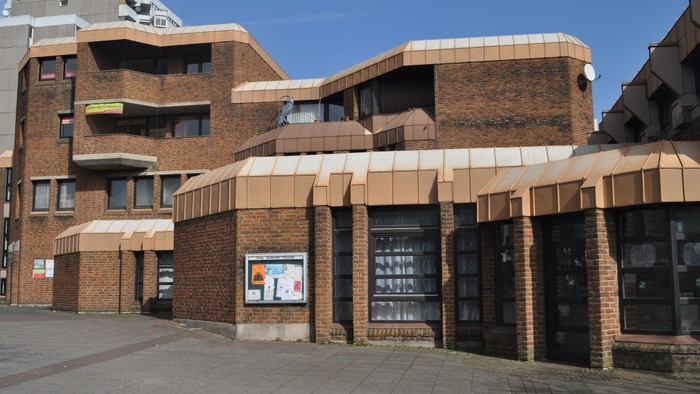 Das Bild zeigt ein modernes Gebäude mit Zinkdach und großen Fenstern.