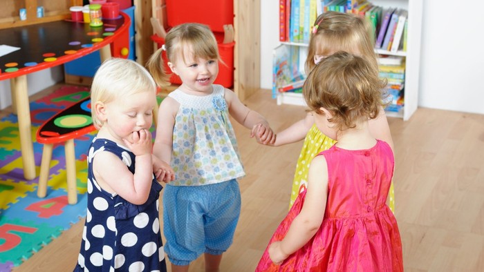 Kleinkinder in der Kita fassen sich an den Händen