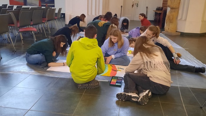 Kinder sitzen im Kreis auf dem Boden und spielen mit Bauklötzen.