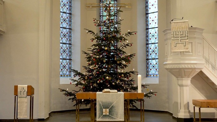 Weihnachtsbaum in der Kirche vor buntem Fenster