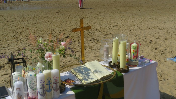 Strandgottesdienst mit Kreuz, Kerzen und Blumen