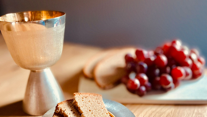 Auf dem Holztisch stehen eine Schale mit Brot und eine Schale mit Trauben