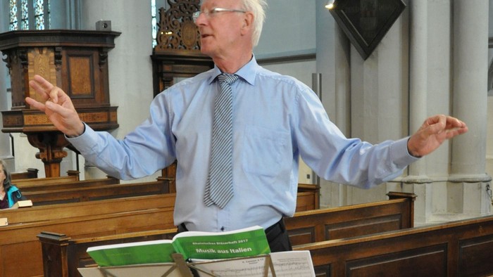 Mann dirigiert Chor in Kirche