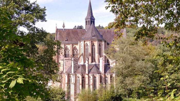 Historische Kirche, umgeben von üppigem Grün mit hohem Turm und detailreicher Steinmetzarbeit.