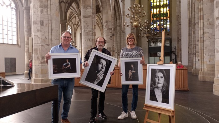 Drei Personen halten Bilder in einer Kirche hoch