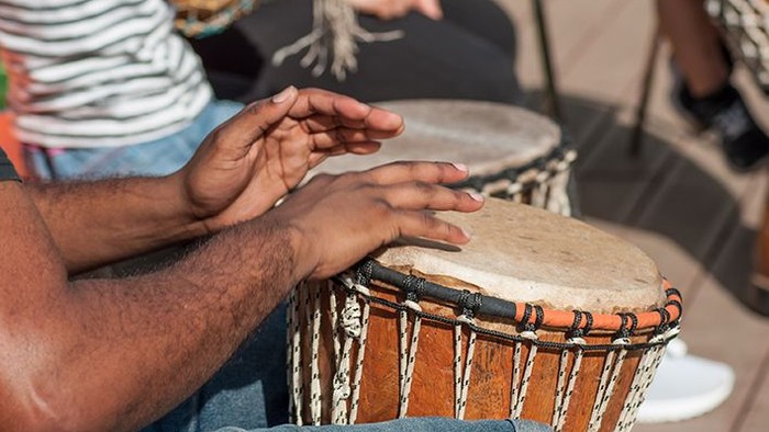 Eine Person spielt eine Trommel mit den Händen.