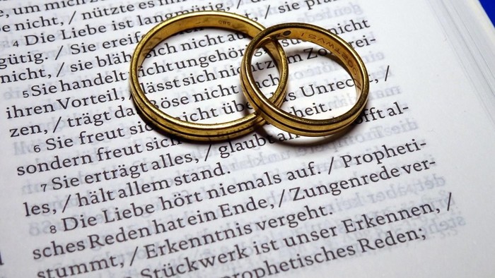 Zwei goldene Ringe auf aufgeschlagenem Buch mit deutschem Text