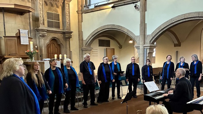 Ein Chor tritt in einer großen Kirchenhalle auf, wobei ein Dirigent die Gruppe leitet.