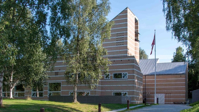 Et moderne bygning med træpanel og flagstang foran