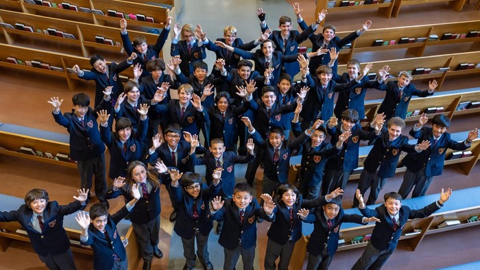 Eine große Gruppe von Kindern in Schuluniformen feiert in einem Saal.