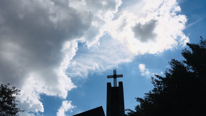 Kirchturm vor blauem Himmel mit Wolken