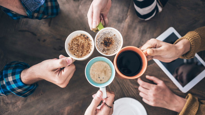 Vier Personen genießen Kaffee und nutzen digitale Geräte.