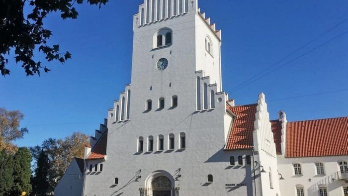 Et stort, hvide kirkebygning med klokketårn og røde tag.