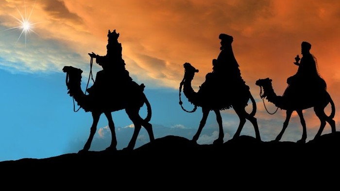 Tre kameler med ridere mod solnedgang