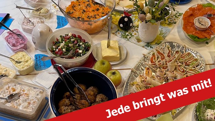 Verschiedenes Essen auf einem Tisch, dazu die Aufschrift "Jede bringt was mit!"