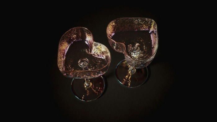 To indviklet designede hjerteformede glas, der støder mod hinanden, med farverige refleksioner mod en mørk baggrund.