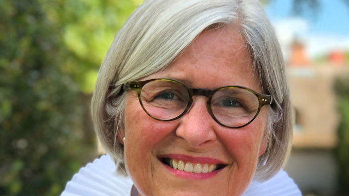 En glad kvinde med kort hår og briller.