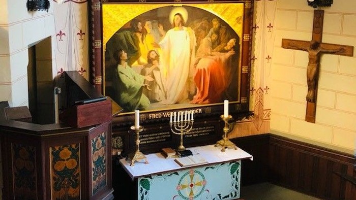 Alter i kirke med alterdish og lysestager foran stor maleri