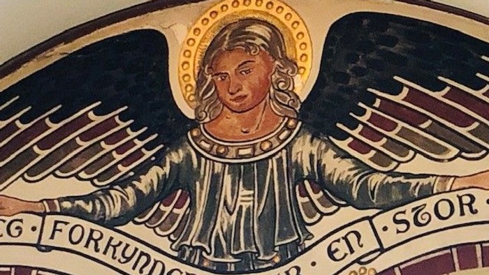 Engel med vinger og krona, der holder banner med latinsk tekst