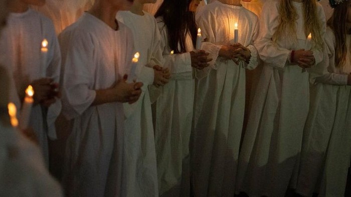 En gruppe kvinder i hvide kider holder lys.