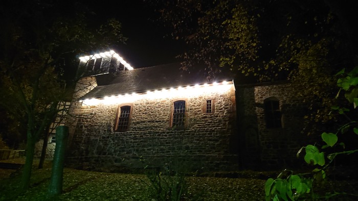 Altes Steinhaus bei Nacht, beleuchtet von einer Laterne
