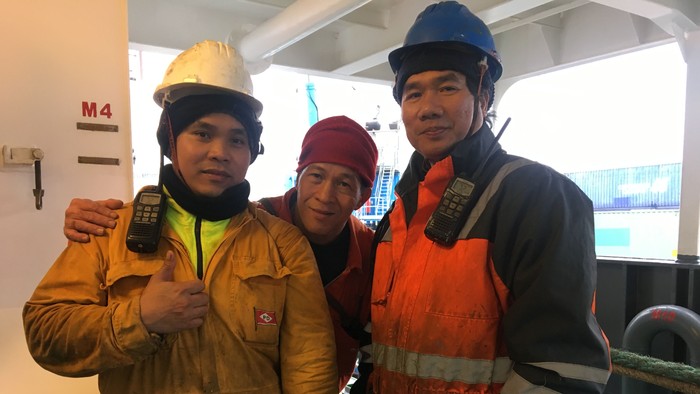 Drei Arbeiter in Sicherheitskleidung auf einem Schiff