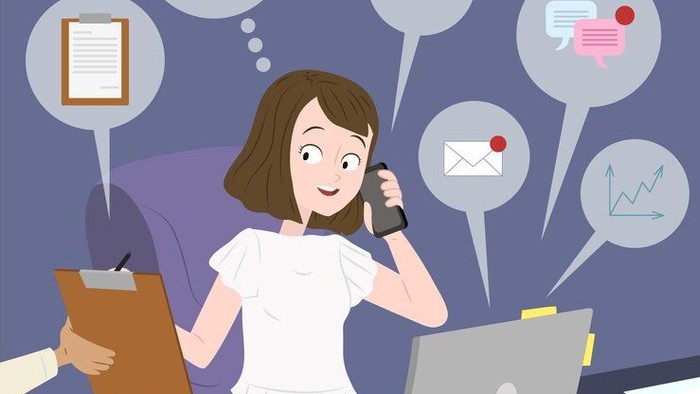 Kvinde på kontor med mobil, laptop og papirer.