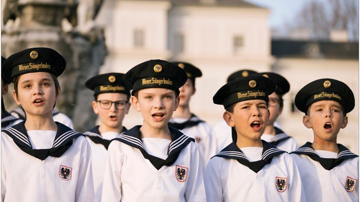 Junge Sänger in Matrosenuniformen singen vor historischem Gebäude