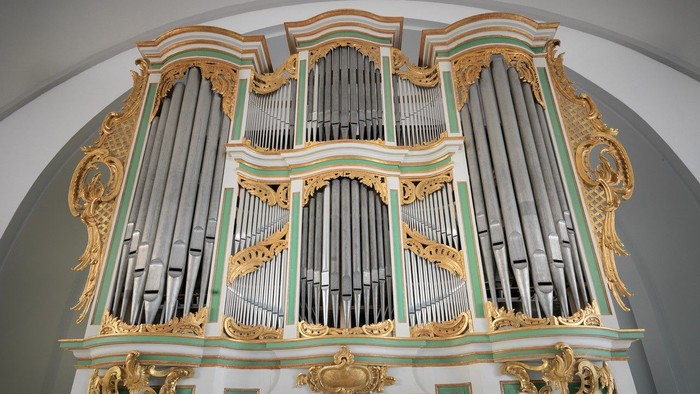 Prachtvolle Kirchenorgel mit goldenen Verzierungen und grün-weißen Akzenten.