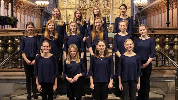 En gruppe kvinder i mørke klæder samlet sig foran en prægtig altertavle i en kirke.