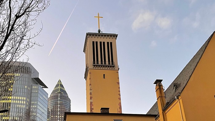 Altes Kirchengebäude vor moderner Stadtlandschaft