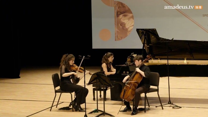 Four musicians performing on stage with string instruments and piano