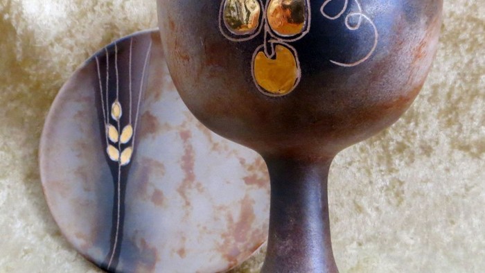 Ein dunkelbrauner Becher mit goldenen Früchten und ein passender Teller