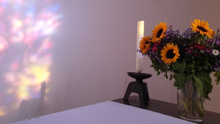 Ein Blumenstrauß mit Sonnenblumen steht auf einem Tisch neben einer Kerze