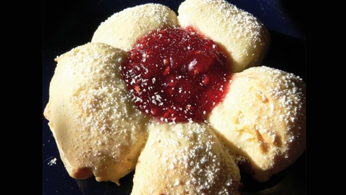 Ein Blumenförmiger Kuchen mit Puderzucker und roter Marmelade in der Mitte