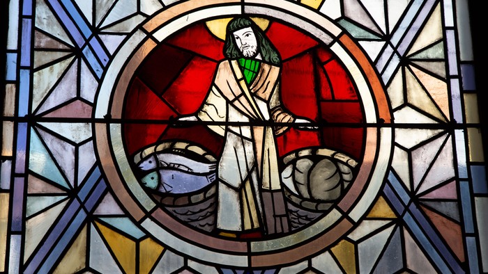 Das gezeigte Buntglasfenster stellt wahrscheinlich eine Szene dar, die mit der Taufe oder der Speisung der Fünftausend in Verbindung steht, da eine Figur, die Jesus ähnelt, mit Körben voller Fische und Brot abgebildet ist